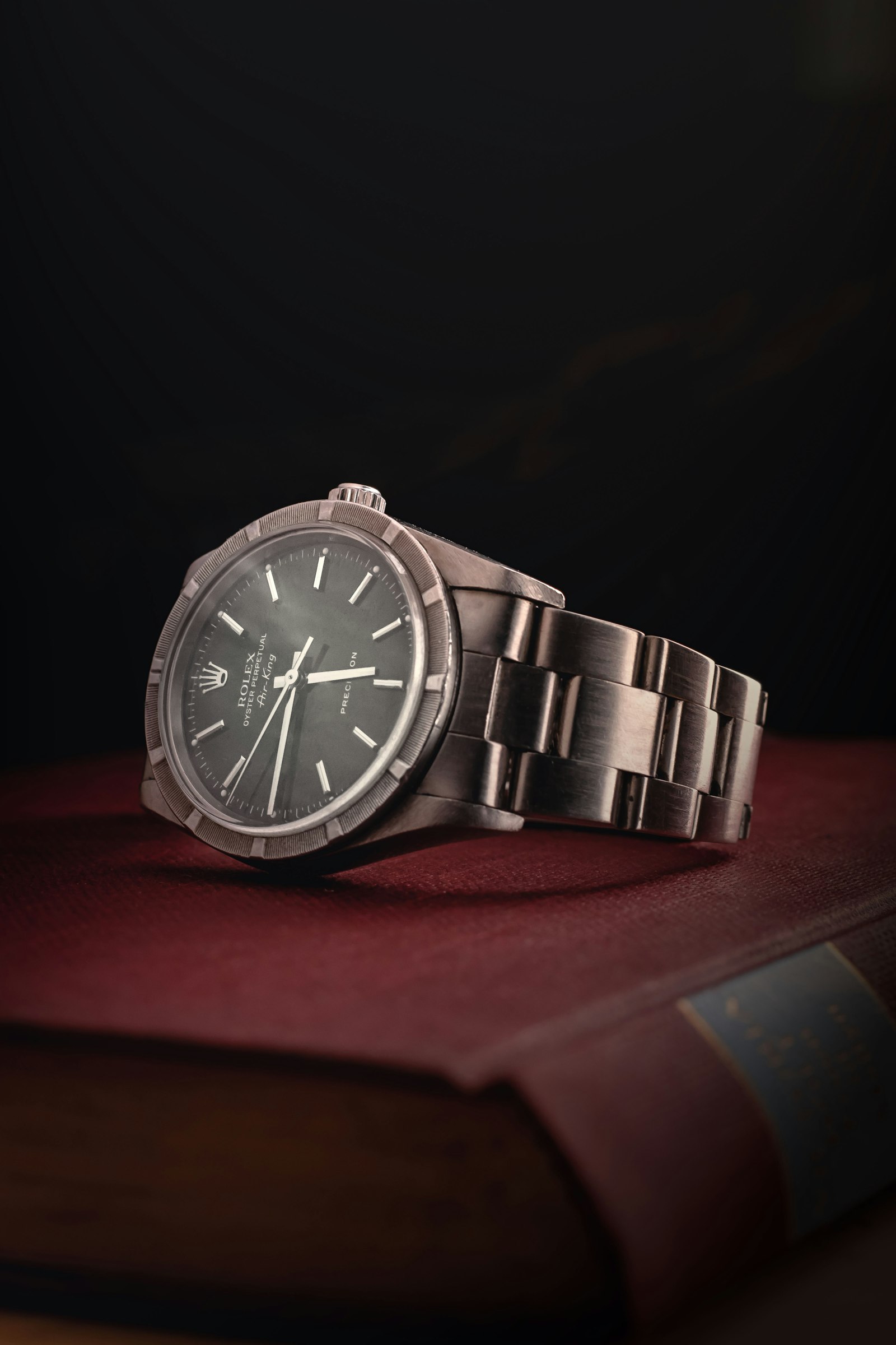A steel Rolex Air-King resting on a leather-bound book