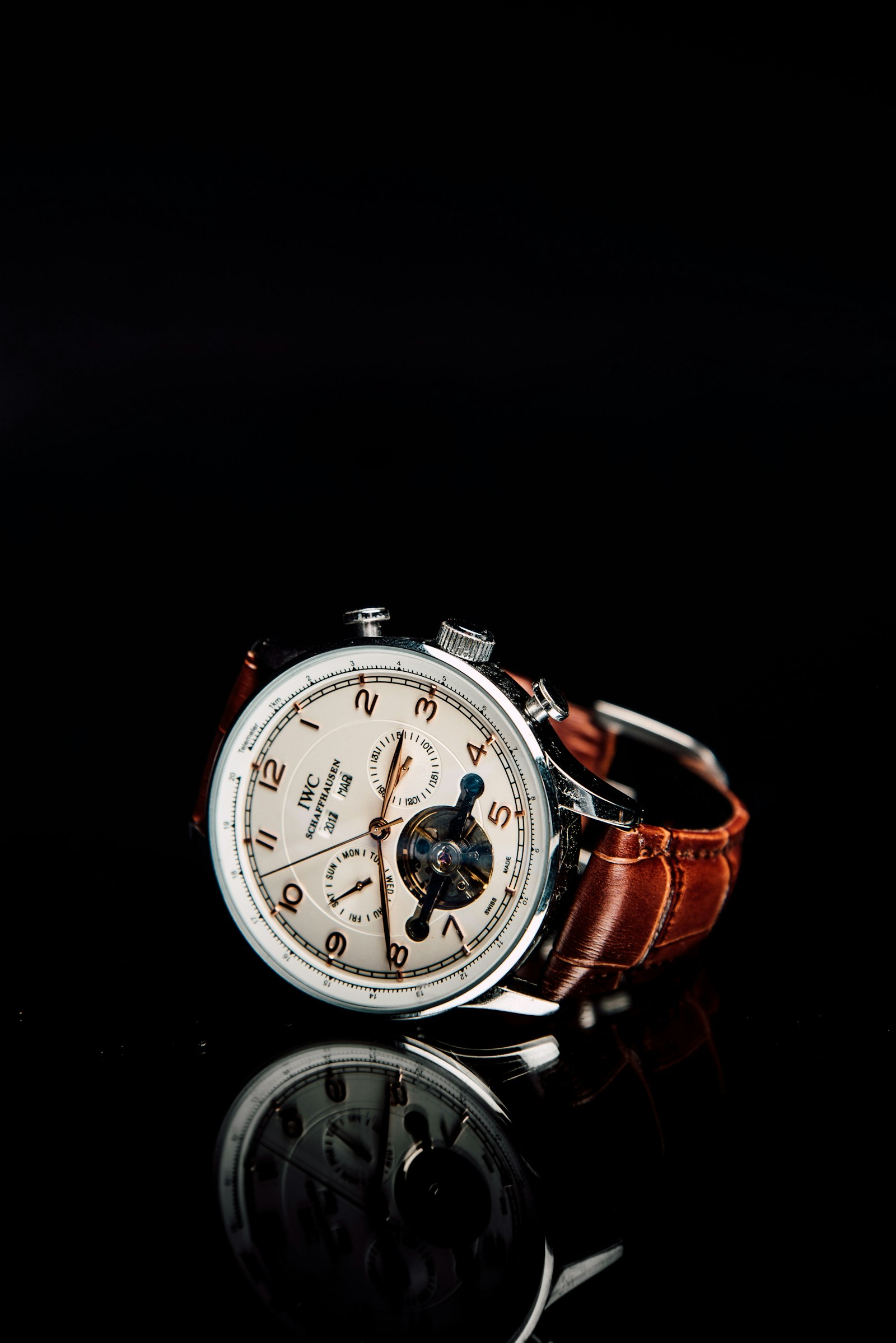 A chronograph on a leather strap photographed on black